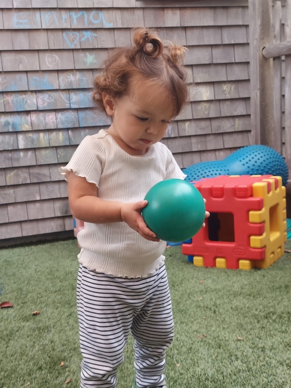 3 children smiling at the camera with one of the children holding a hamburger